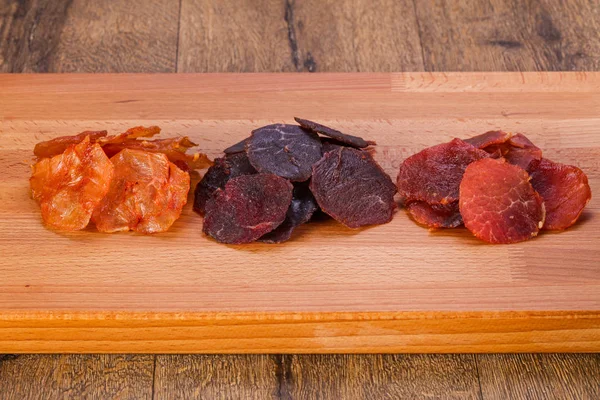 Dry meat snack over the wooden background