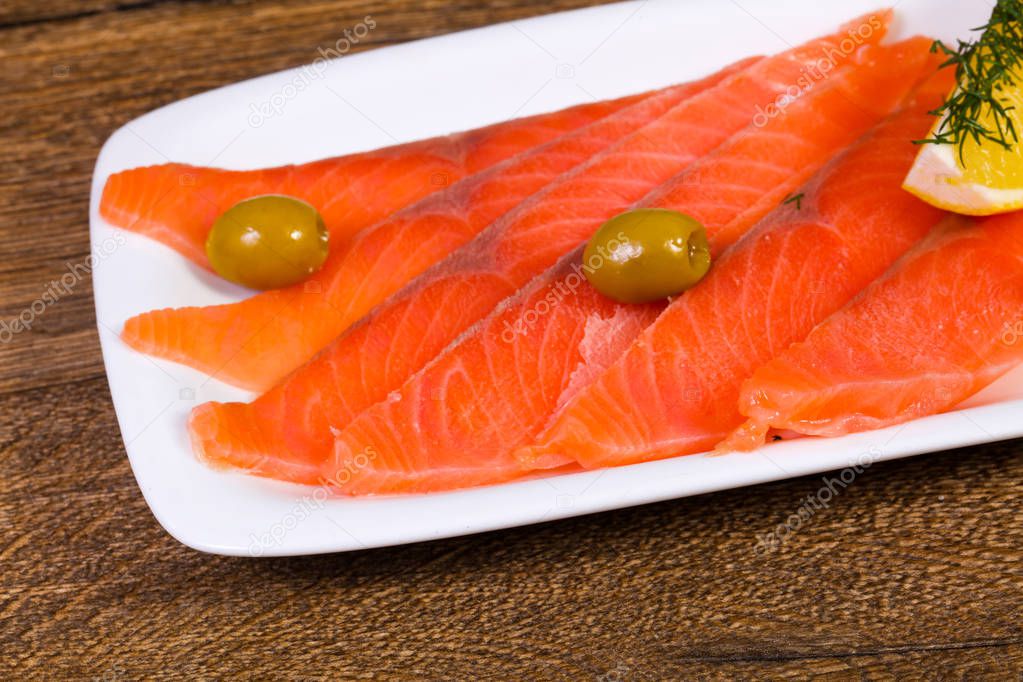 Sliced salmon with lemon and olives