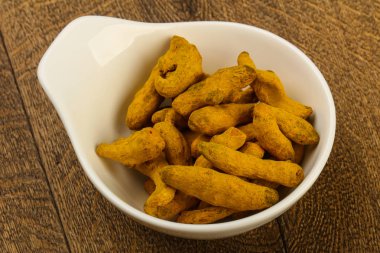 Tumeric kökü yığın içinde kase ahşap arka plan üzerinde