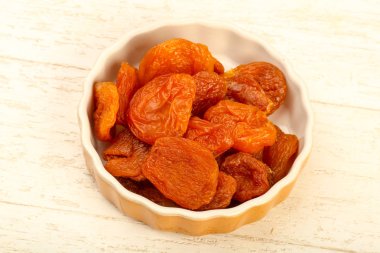 Kuru Kayısı yığın içinde kase ahşap arka plan üzerinde