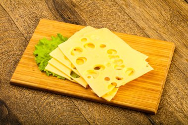 Ahşap arka plan üzerinde dilimlenmiş peynir salata yaprakları