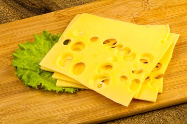 Ahşap arka plan üzerinde dilimlenmiş peynir salata yaprakları