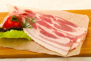 Raw bacon served dill over the wooden background clipart