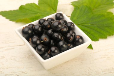 Olgun siyah kuş üzümü ile yaprak kase