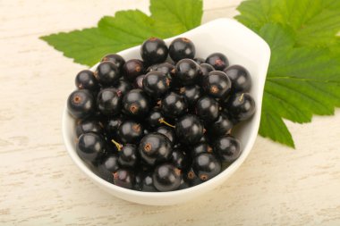 Olgun siyah kuş üzümü ile yaprak kase