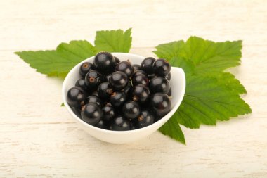 Olgun siyah kuş üzümü ile yaprak kase