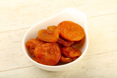 Kuru Kayısı yığın içinde kase ahşap arka plan üzerinde