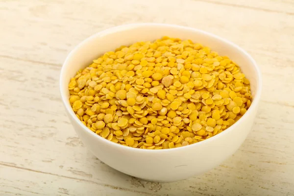 Yellow lentil ready for cooking over wooden background