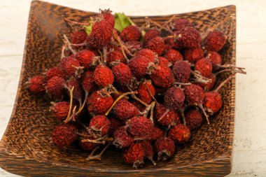 Kase ahşap arka plan üzerinde kuru alıç yığın