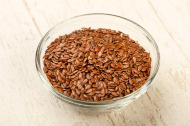 Kızartma keten tohumları ahşap arka planda kasede yığılıyor.