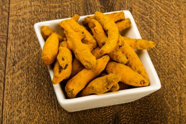 Tumeric kökü yığın içinde kase ahşap arka plan üzerinde