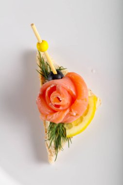 Beyaz tabakta somonlu sandviç.