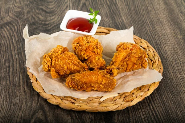 Crispy chicken wings with ketchup over wooden background