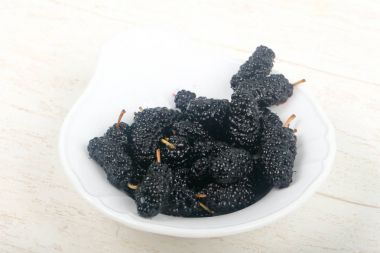 Black Mulberries heap on white table clipart