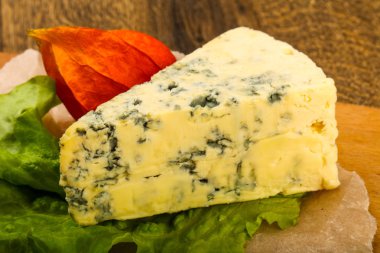 Ahşap arka planda salata yapraklı mavi peynir.