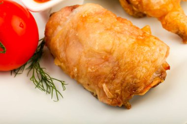 Pişmiş tavuk budu beyaz masa üzerinde domates ile