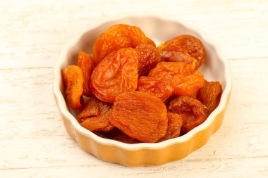 Kuru Kayısı yığın içinde kase ahşap arka plan üzerinde