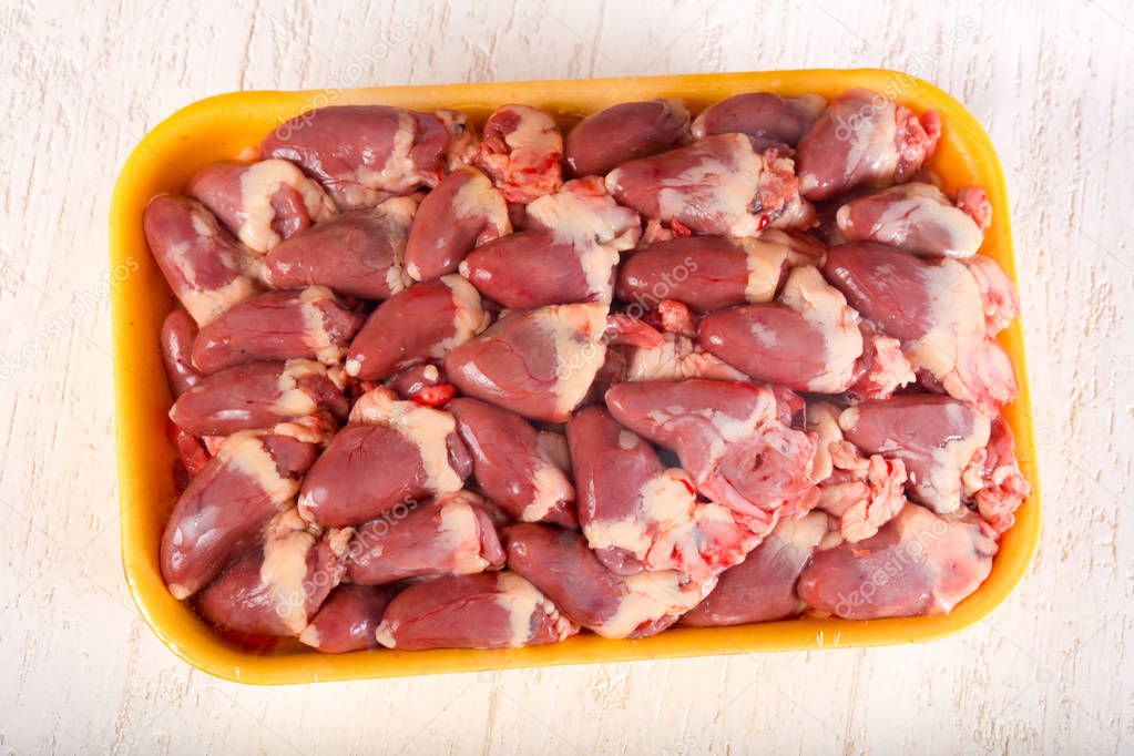 Raw chicken hearts for cooking over wooden background