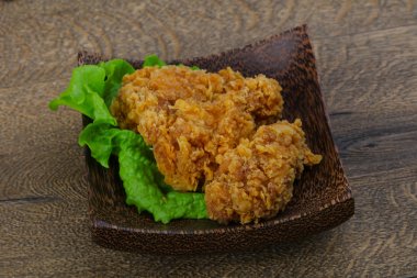 Çıtır tavuk kanatları ile salata yaprakları üzerinde ahşap arka plan