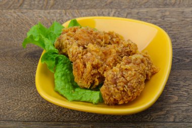 Çıtır tavuk kanatları ile salata yaprakları üzerinde ahşap arka plan