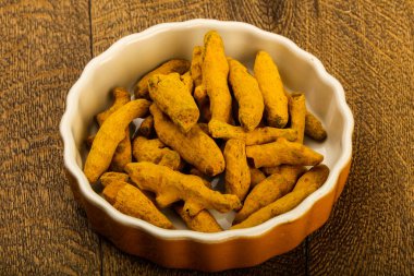 Tumeric kökü yığın içinde kase ahşap arka plan üzerinde