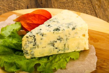 Ahşap arka planda salata yapraklı mavi peynir.