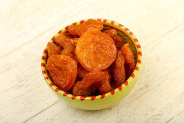 Kuru Kayısı yığın içinde kase ahşap arka plan üzerinde