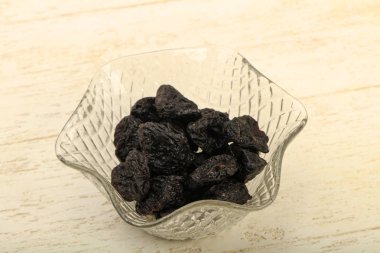 Kurumuş erikler ahşap arka planda kasede yığılıyor.