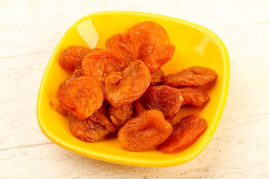 Kuru Kayısı yığın içinde kase ahşap arka plan üzerinde