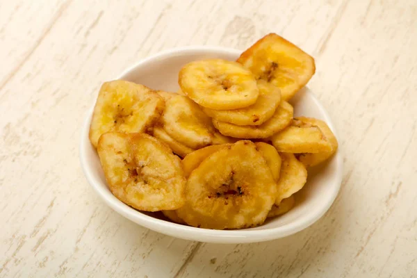 Dry banana chips over wooden background