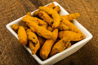 Tumeric kökü yığın içinde kase ahşap arka plan üzerinde