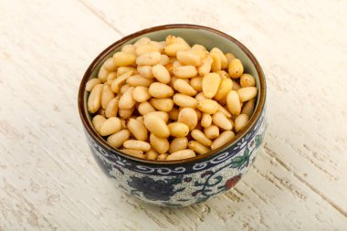 Sedir fındık yığın içinde kase ahşap arka plan üzerinde