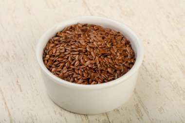 Kızartma keten tohumları ahşap arka planda kasede yığılıyor.