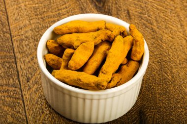 Tumeric kökü yığın içinde kase ahşap arka plan üzerinde