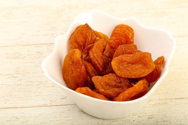 Kuru Kayısı yığın içinde kase ahşap arka plan üzerinde