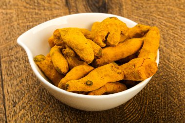 Tumeric kökü yığın içinde kase ahşap arka plan üzerinde