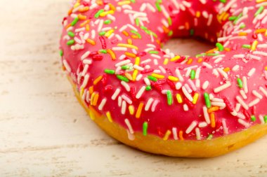 Pembe tatlı çörek ahşap arka plan üzerinde buzlu.