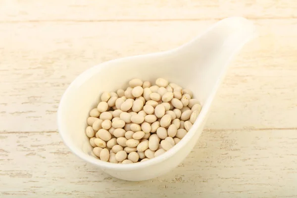 Dry white beans in the bowl over wooden background