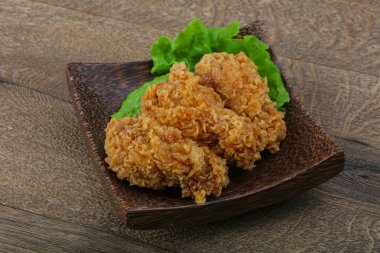 Çıtır tavuk kanatları ile salata yaprakları üzerinde ahşap arka plan