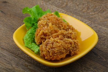 Çıtır tavuk kanatları ile salata yaprakları üzerinde ahşap arka plan