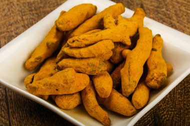 Tumeric kökü yığın içinde kase ahşap arka plan üzerinde