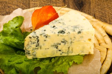 Ahşap arka planda salata yapraklı mavi peynir.