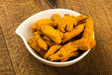 Tumeric kökü yığın içinde kase ahşap arka plan üzerinde