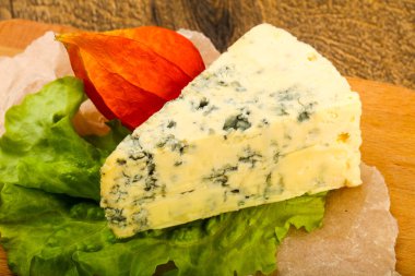 Ahşap arka planda salata yapraklı mavi peynir.