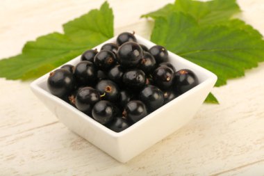 Olgun siyah kuş üzümü ile yaprak kase