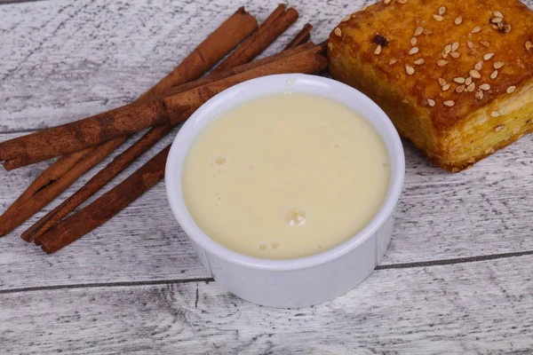 Condenced milk in the bowl with sinnamon and pastry — Stock Photo, Image