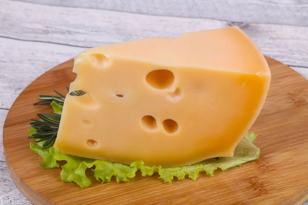 Queso Maasdam en la tabla sirve hojas de ensalada —  Fotos de Stock