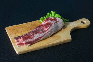 Tahtanın üzerinde çiğ domuz pastırması salata ve kekik servis edildi.