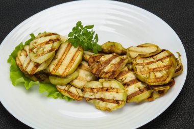 Izgara patlıcan dilimleri fesleğen ve salata yaprakları servis edilir.