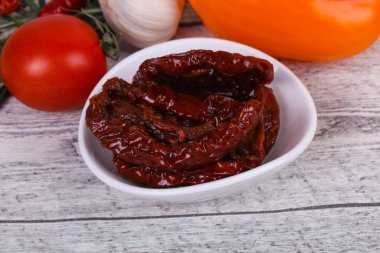 Kavanozda kurutulmuş domates, zeytinyağı biberiye, salata yaprakları ve sarımsak.